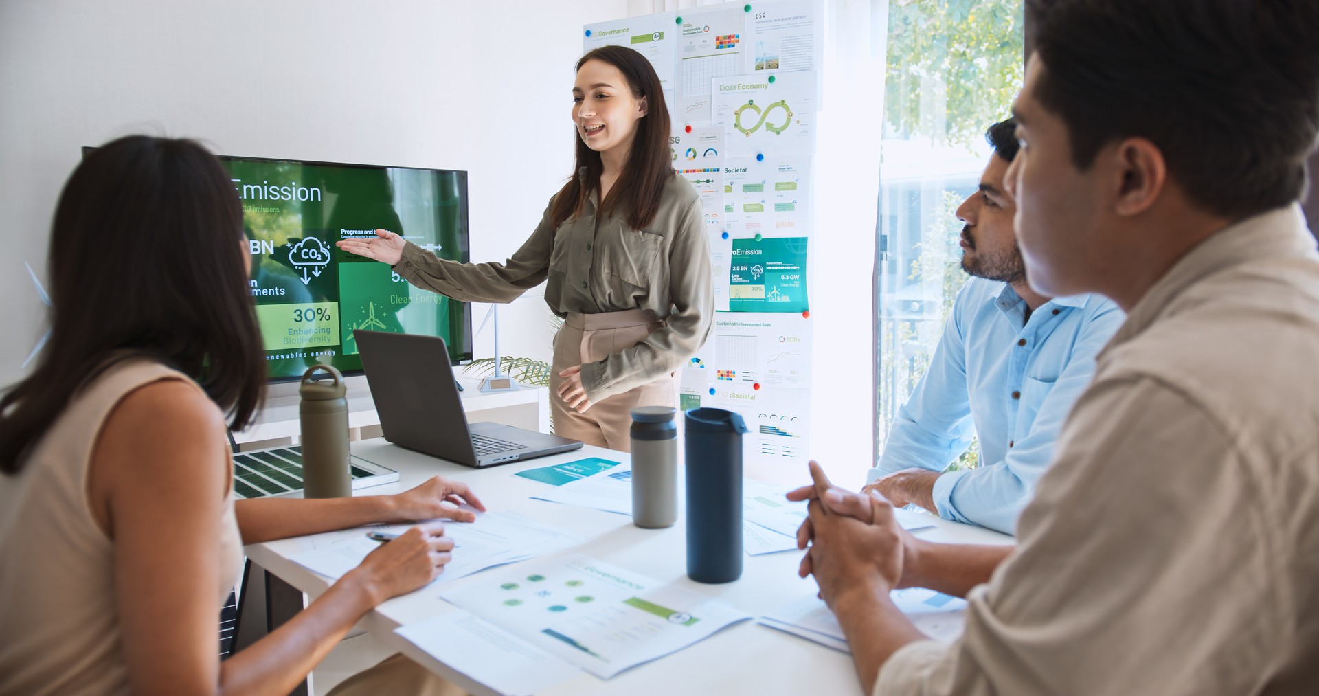 Asian woman lead young group of multiethnic businesspeople in team meeting, using laptop computer for ESG topic presentation on monitor. Sustainable business practice, people work at home concept